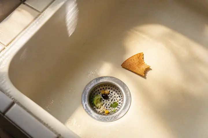 Rice and cilantro in a drain beside bitten tortilla