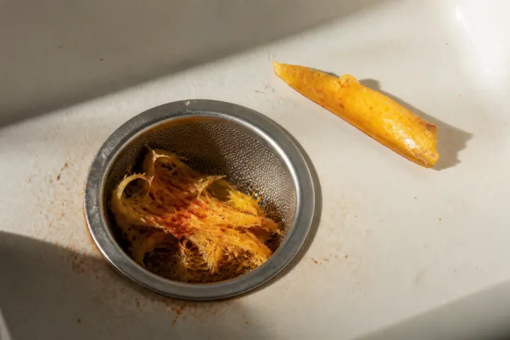 Mango fibers and chili salt in mesh beside a mango slice