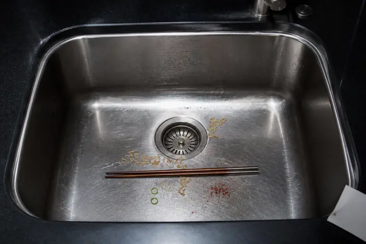 Noodle traces and chopsticks in a stainless sink