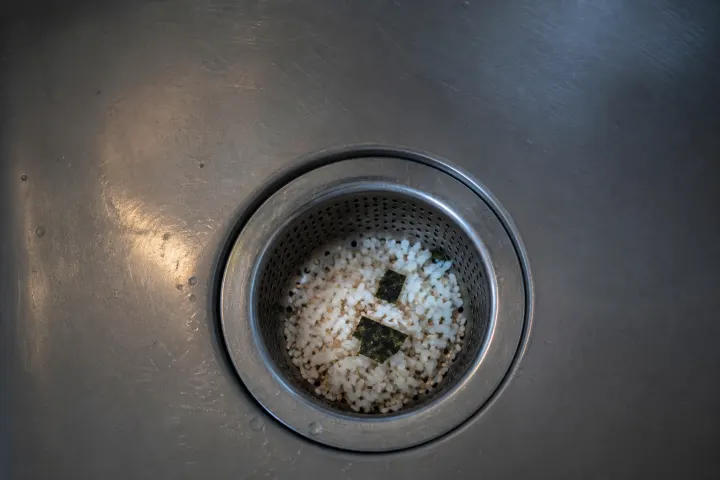 Rice, nori and sesame caught in a stainless sink strainer